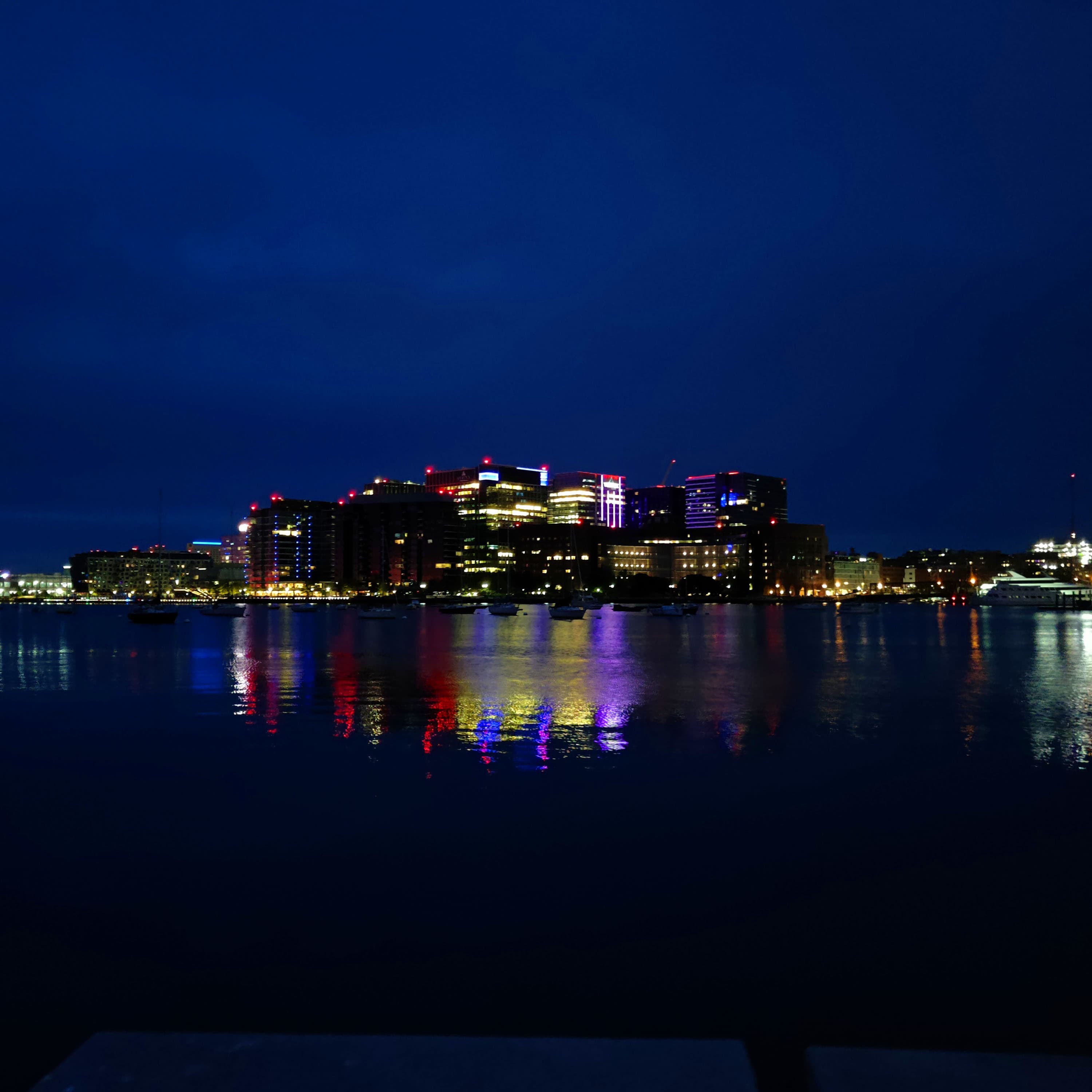 the seaport district lit up and viewed from a wharf in downtown at night