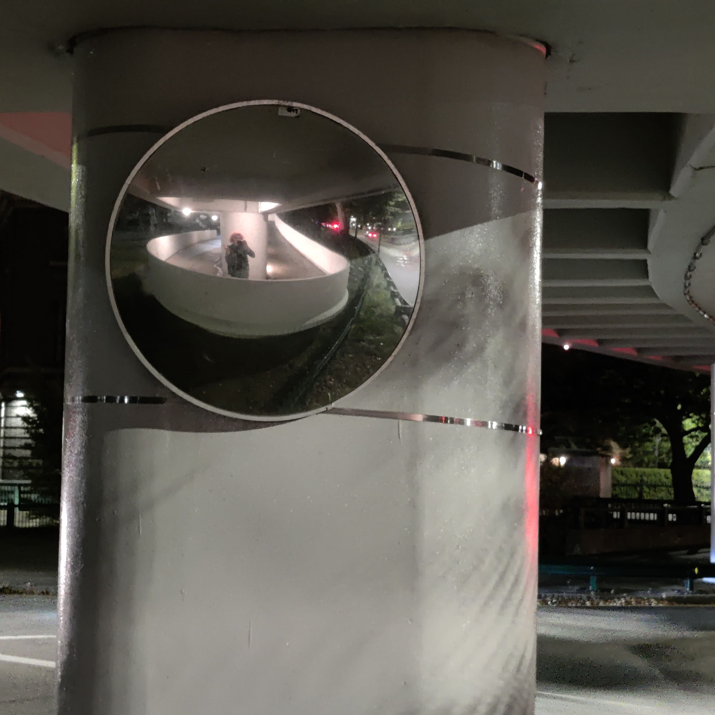 a self-portrait in a convex mirror on a footbridge at night